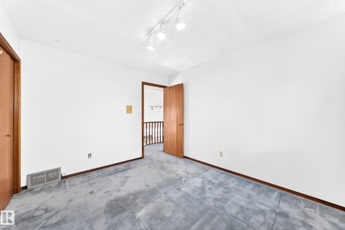 White walls, wood-finish doors, track lighting, and soft carpet - 4208 Ramsay Road Nw, Edmonton, AB 