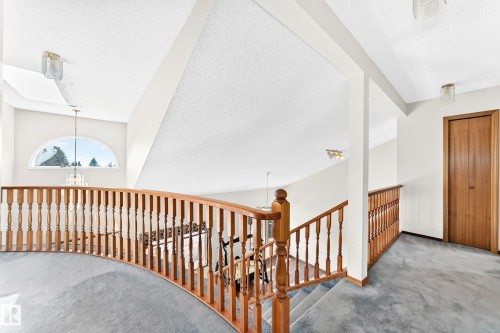 Upper-level landing with light wood-finish railings, arched window, and recessed lighting - 4208 Ramsay Road Nw, Edmonton, AB 