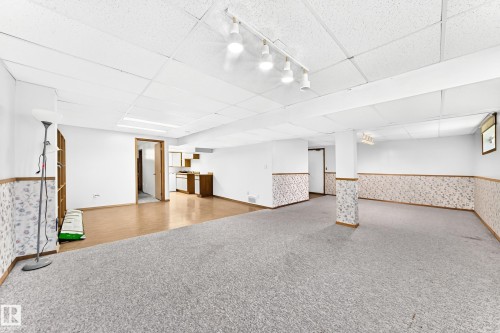 Spacious finished basement featuring track lighting, drop ceiling, and mixed flooring - 4208 Ramsay Road Nw, Edmonton, AB 