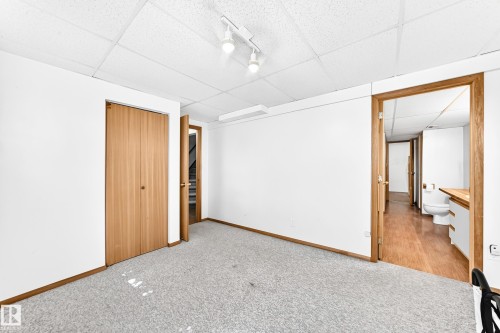 Light gray carpeting, white painted walls, wood-finish bi-fold closet doors, wood-finish trim, and recessed ceiling lighting - 4208 Ramsay Road Nw, Edmonton, AB 