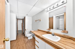 Wood-finish flooring with a white vanity featuring a wood-finish countertop - 