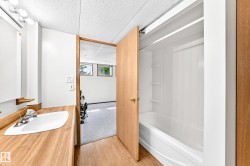 White drop-in bathtub with integrated shelving, wood-finish flooring, and a wood-finish vanity with an integrated sink - 