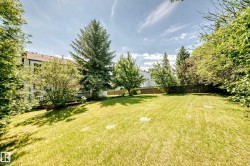 Expansive green space featuring mature trees and a sloped lawn - 