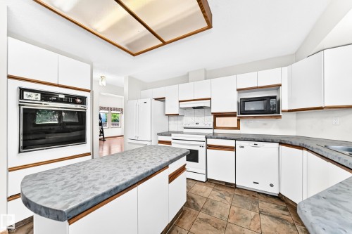 Kitchen with white cabinetry, built-in oven, integrated microwave, and a central island with a contrasting countertop - 4208 Ramsay Road Nw, Edmonton, AB 