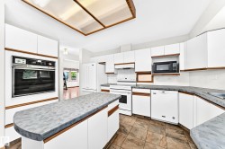 Kitchen with white cabinetry, built-in oven, integrated microwave, and a central island with a contrasting countertop - 
