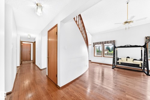 Wood-finish flooring, white walls, and a curved staircase with wood railing - 4208 Ramsay Road Nw, Edmonton, AB 