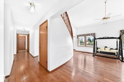 Wood-finish flooring, white walls, and a curved staircase with wood railing - 