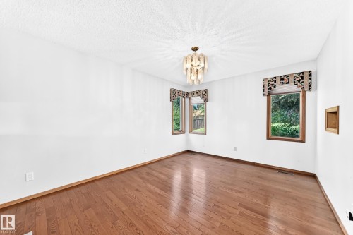 Hardwood flooring, multiple windows, built-in wall niche, and a decorative chandelier - 4208 Ramsay Road Nw, Edmonton, AB 