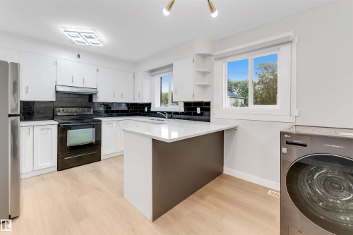 White cabinetry, black subway tile backsplash, white countertops, stainless steel refrigerator, and light wood-finish flooring - 7928 82 Avenue Nw, Edmonton, AB 