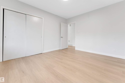 Light-toned wood-finish flooring, white walls, and a white ceiling contribute to the bright interior - 7928 82 Avenue Nw, Edmonton, AB 