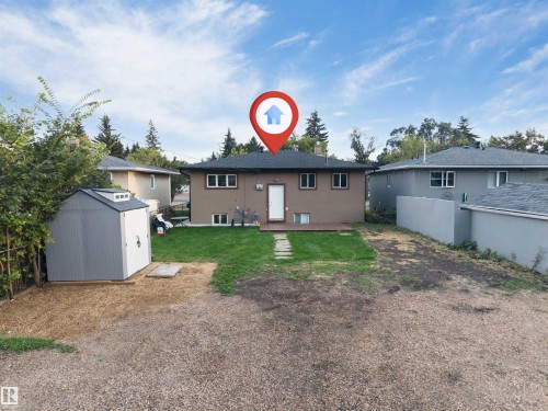 Expansive backyard featuring a wood deck, stone pathway, and manicured lawn - 7928 82 Avenue Nw, Edmonton, AB 