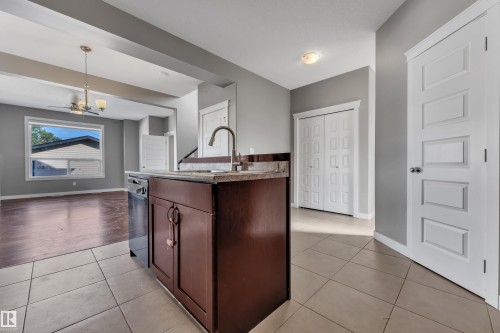 Kitchen island with built-in dishwasher, stainless steel faucet, and granite-style countertop - 11421 82 Street Nw, Edmonton, AB 
