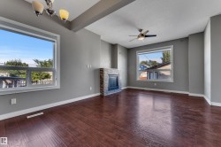 Wood-finish flooring, stone-clad fireplace, integrated ceiling fan, and recessed lighting - 