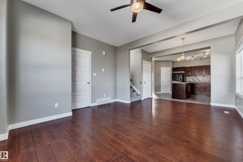 Spacious living area featuring wood-finish flooring, a ceiling fan, and light gray walls - 11421 82 Street Nw, Edmonton, AB 