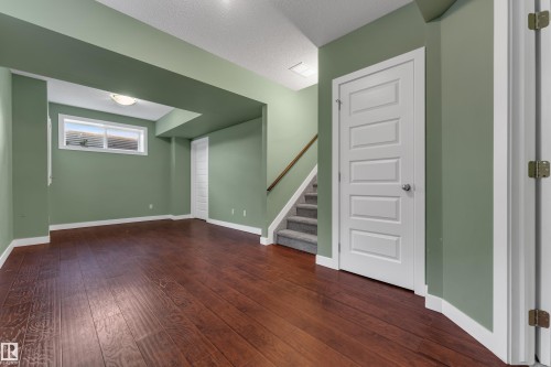 Wood-finish flooring, recessed lighting, egress window, white interior doors, and a carpeted staircase - 11421 82 Street Nw, Edmonton, AB 