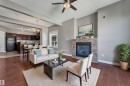 Wood-finish flooring, stone-clad fireplace, built-in ceiling beams, recessed lighting, and a modern ceiling fan - 11421 82 Street Nw, Edmonton, AB 