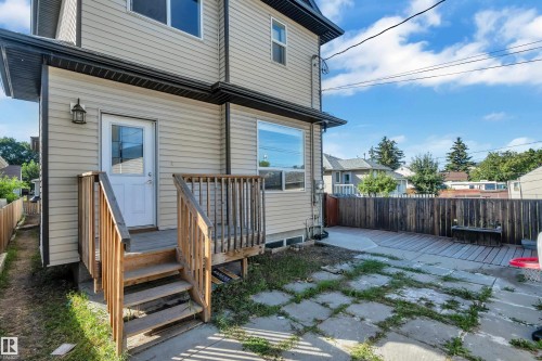 Rear exterior with light-toned siding, dark rain gutters, and a wood-slatted fence - 11421 82 Street Nw, Edmonton, AB 