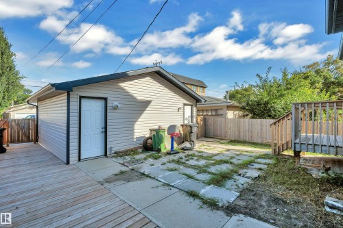 Detached garage with siding exterior, wood deck, wood privacy fencing, and concrete patio - 11421 82 Street Nw, Edmonton, AB 
