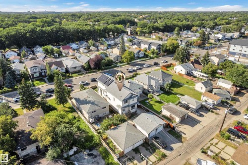 Aerial view showcasing this Colonial-style residence featuring a two-car attached garage, expansive driveway, manicured lawn with mature landscaping, and a substantial secondary outbuilding - 11421 82 Street Nw, Edmonton, AB 