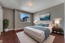 Warm wood-finish flooring, neutral wall tones, and a single window with a black curtain rod - 11421 82 Street Nw, Edmonton, AB 
