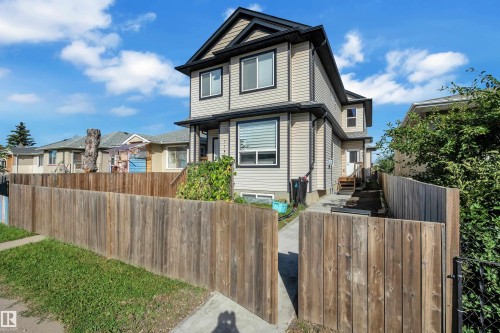 Two-story exterior with light-colored siding, black trim, and a dark roof - 11421 82 Street Nw, Edmonton, AB 