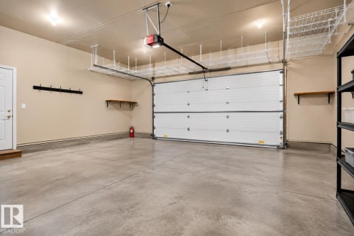 Concrete flooring, overhead storage racks, built-in shelving, overhead lighting, and an automatic garage door opener - 941 Picard Drive Nw, Edmonton, AB 