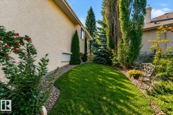 Manicured lawn with a curved stone-lined bed, mature trees, and shrubs with red berries - 