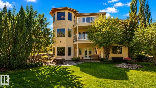 Multi-level property with an expansive lawn, mature trees, a ground-level patio, and upper-level balconies featuring glass railings - 941 Picard Drive Nw, Edmonton, AB 