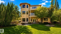 Multi-level property with an expansive lawn, mature trees, a ground-level patio, and upper-level balconies featuring glass railings - 