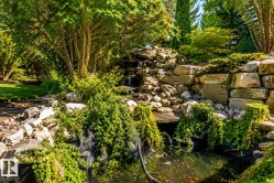 Water feature with cascading falls and a pond, surrounded by lush plantings and natural stone hardscaping - 