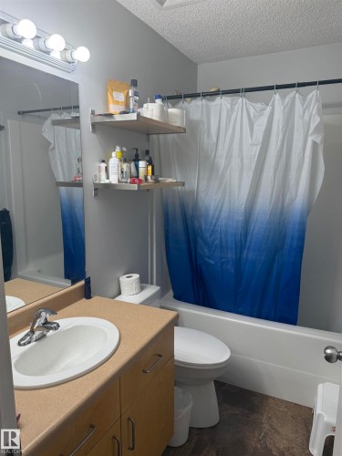 Bathroom featuring a wood-finish vanity with an integrated sink, a full-width mirror, and a bathtub with a shower - 124 Ward Crescent Nw Nw, Edmonton, AB 