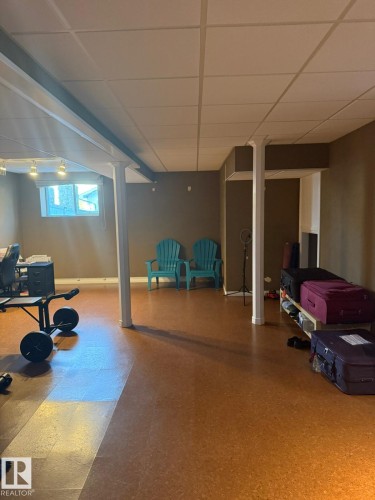 Spacious room featuring a drop ceiling, recessed lighting, support columns, and durable cork flooring - 124 Ward Crescent Nw Nw, Edmonton, AB 