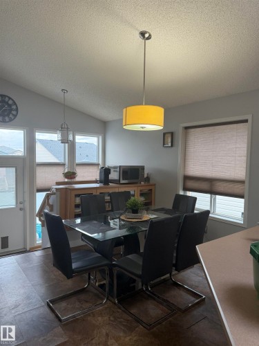 Angled ceiling with a drum pendant light fixture, wood-finish flooring, and a built-in wood-tone cabinet - 124 Ward Crescent Nw Nw, Edmonton, AB 