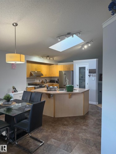 Spacious kitchen with a central island, light wood-finish cabinetry, and stainless steel appliances - 124 Ward Crescent Nw Nw, Edmonton, AB 