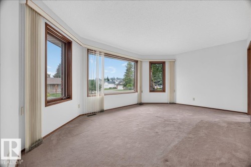 Bay window configuration with multiple windows, wood-finish window frames, and neutral carpeting - 2907 49 Street Nw, Edmonton, AB 