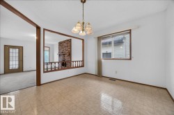 Tiled flooring, overhead chandelier, window with a valance, and a structural opening to an adjacent room featuring a brick fireplace - 