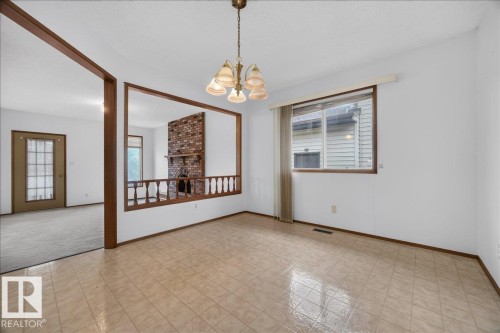 Tiled flooring, overhead chandelier, window with a valance, and a structural opening to an adjacent room featuring a brick fireplace - 2907 49 Street Nw, Edmonton, AB 