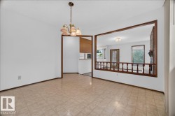 Tile flooring, suspended chandelier, wood-trimmed archway, interior wood balustrade, and brick fireplace - 