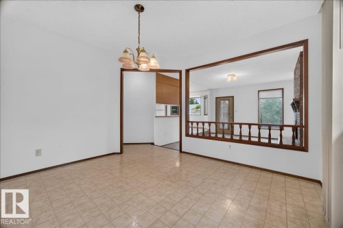 Tile flooring, suspended chandelier, wood-trimmed archway, interior wood balustrade, and brick fireplace - 2907 49 Street Nw, Edmonton, AB 