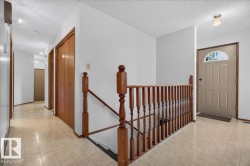 Tiled flooring throughout, wood-finish interior doors, wooden staircase railing, and a light-colored entry door with an arched transom window - 
