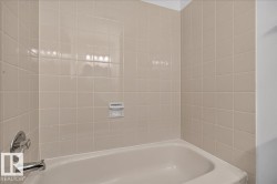 Bathtub with integrated soap dish, chrome fixtures, and square tile surround - 