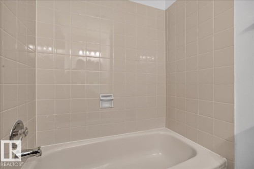 Bathtub with integrated soap dish, chrome fixtures, and square tile surround - 2907 49 Street Nw, Edmonton, AB 