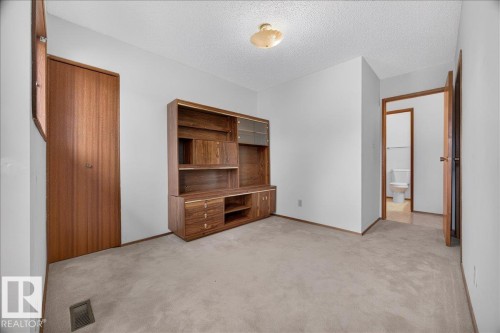 Recessed ceiling light fixture, wood-finish doors, built-in wooden shelving unit with cabinet storage, light neutral-toned carpeting, and white wall finishes - 2907 49 Street Nw, Edmonton, AB 