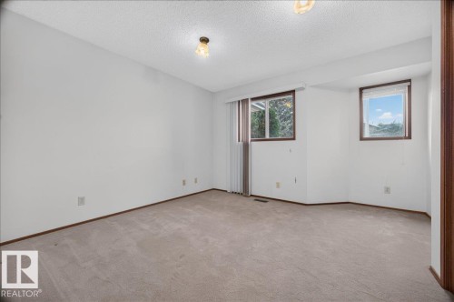 Neutral-toned wall-to-wall carpeting, white painted walls, and two windows with wood-frame trim - 2907 49 Street Nw, Edmonton, AB 