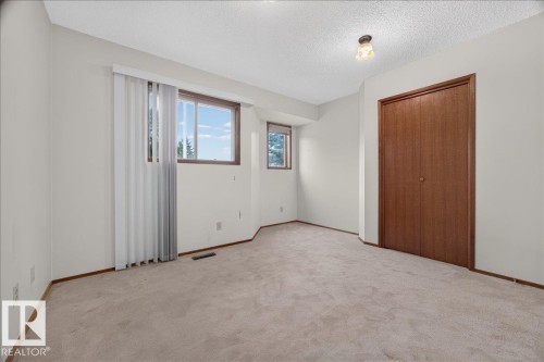 Neutral tone carpeting, a pair of windows providing natural light, and a built-in closet with wood-finish doors - 2907 49 Street Nw, Edmonton, AB 