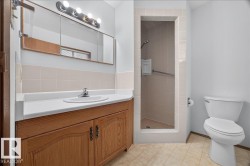 Bathroom featuring a wood-finish vanity with an integrated sink, white countertop, and tiled backsplash - 
