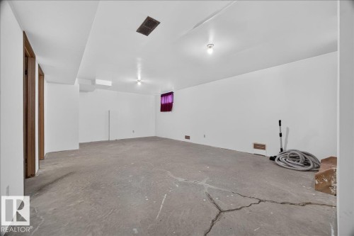 Expansive unfinished lower level with concrete flooring, white painted walls, and overhead lighting - 2907 49 Street Nw, Edmonton, AB 