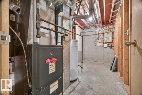 Utility room featuring a furnace, water heater, exposed wood framing, and concrete flooring - 2907 49 Street Nw, Edmonton, AB 
