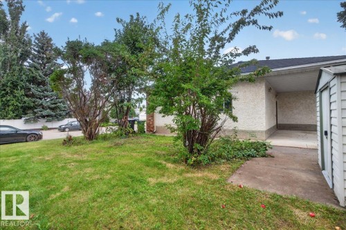 Stucco exterior with a covered carport, pitched shingle roof, and a detached storage shed - 2907 49 Street Nw, Edmonton, AB 