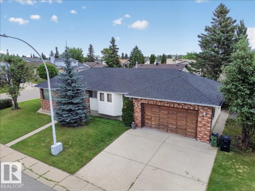 Brick exterior with a shingled roof, an attached garage with a wood-finish door, and a concrete driveway - 2907 49 Street Nw, Edmonton, AB 